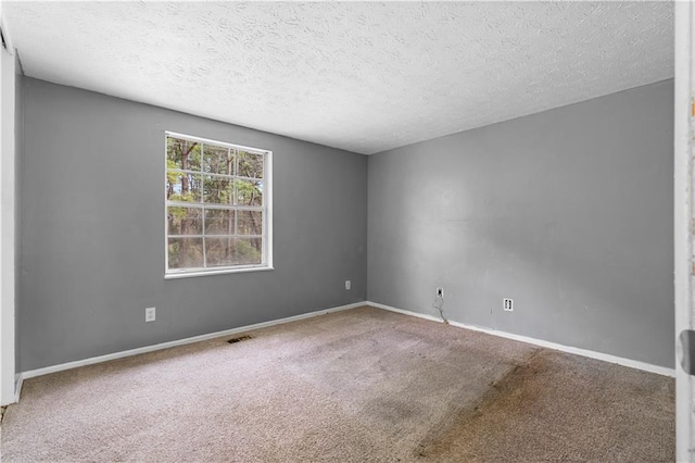 carpeted empty room with visible vents, a textured ceiling, and baseboards