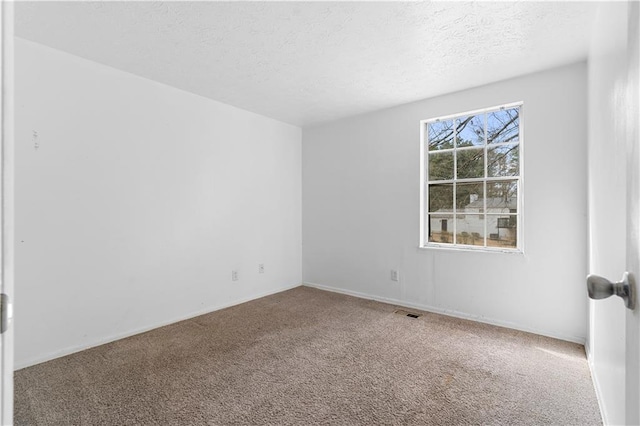 empty room with carpet floors, visible vents, and a textured ceiling