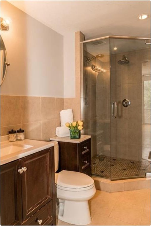 bathroom featuring walk in shower, tile patterned flooring, toilet, vanity, and tile walls