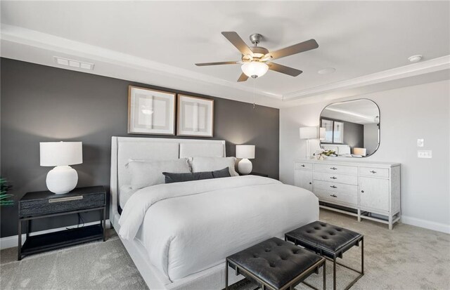 bedroom featuring visible vents, baseboards, a raised ceiling, ceiling fan, and light colored carpet