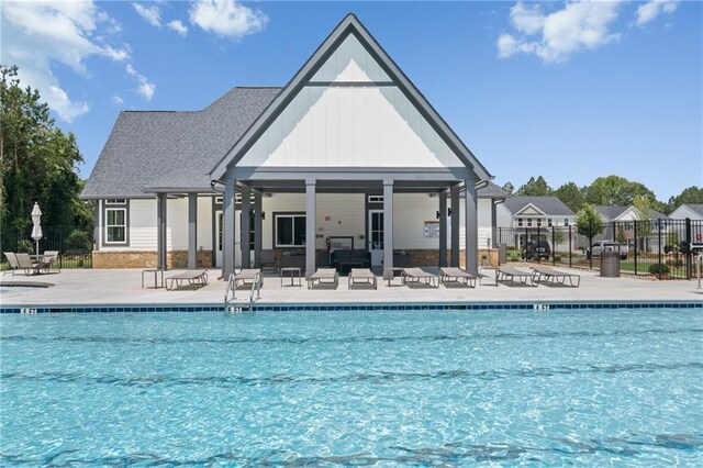 pool featuring fence, an outdoor structure, a patio, and a storage structure