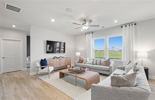living area with baseboards, light wood finished floors, ceiling fan, and visible vents