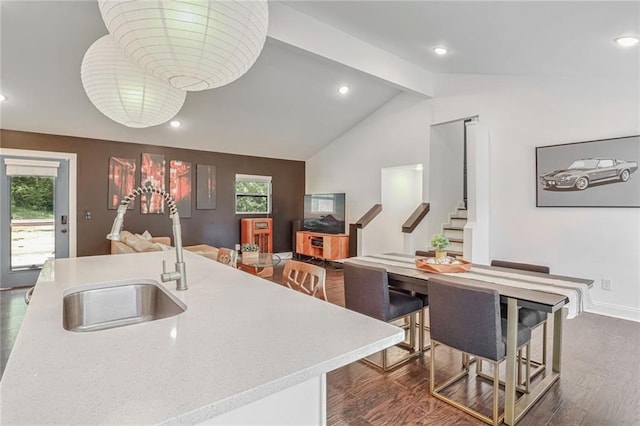 kitchen with sink, vaulted ceiling with beams, dark hardwood / wood-style flooring, a breakfast bar, and a center island with sink