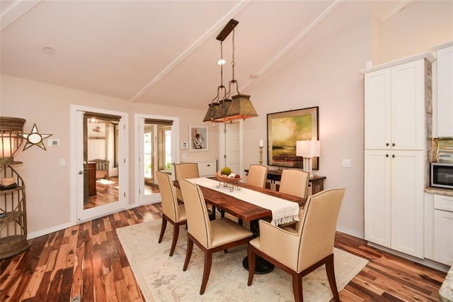 dining room featuring lofted ceiling, baseboards, and wood finished floors