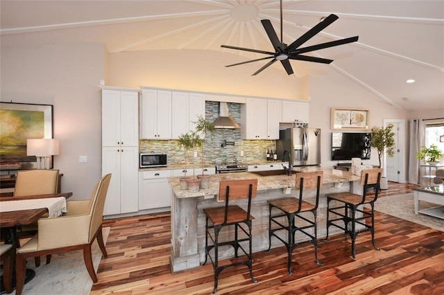 kitchen with light stone countertops, a kitchen island with sink, a breakfast bar area, and stainless steel appliances