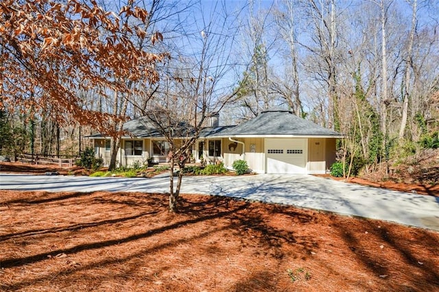 ranch-style house featuring driveway, a chimney, and an attached garage