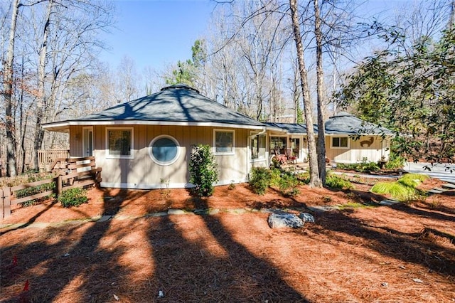 view of front of house featuring driveway, covered porch, and fence