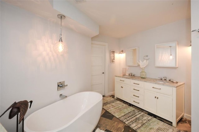 bathroom with double vanity, a freestanding tub, baseboards, and a sink