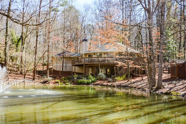 rear view of property featuring a deck with water view and a chimney