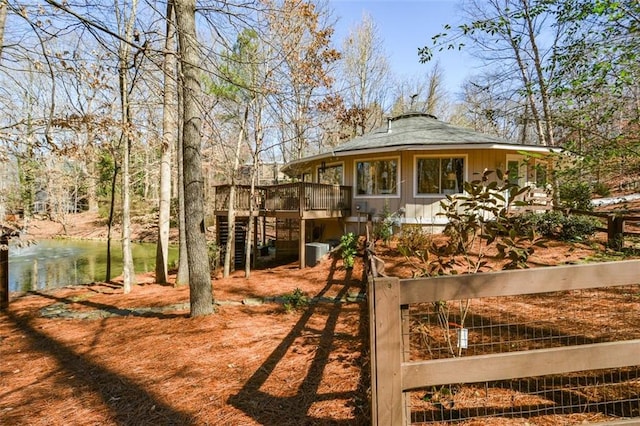 view of yard featuring a deck with water view, fence, and central AC