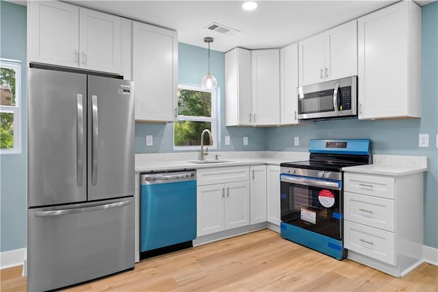 5233 Groovers Landing Rd SE, Acworth, GA 30101 - kitchen with appliances with stainless steel finishes, light countertops, white cabinets, light wood-type flooring, and hanging light fixtures