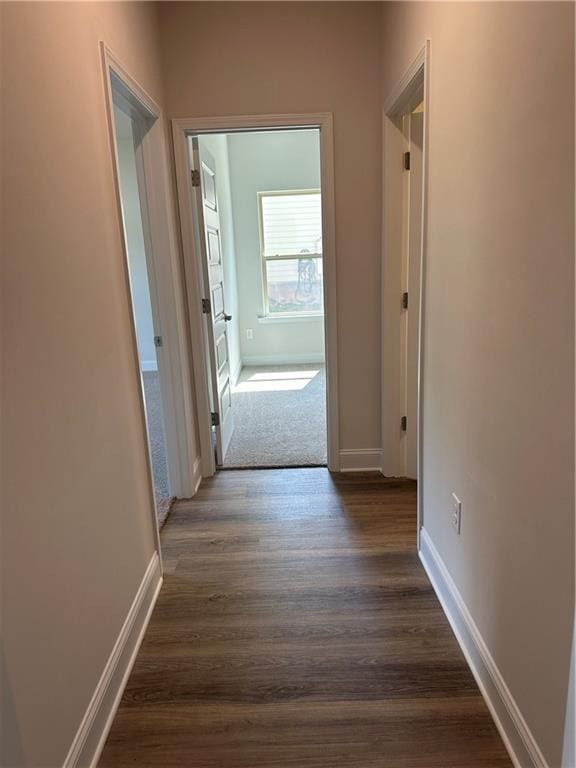 corridor with dark wood finished floors and baseboards