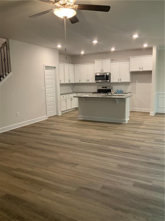 kitchen featuring ceiling fan, dark hardwood / wood-style floors, a kitchen island with sink, white cabinets, and appliances with stainless steel finishes