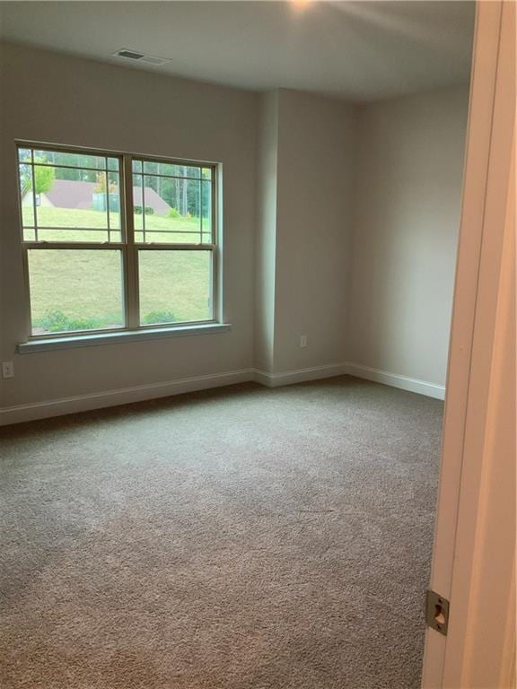 carpeted spare room featuring visible vents and baseboards