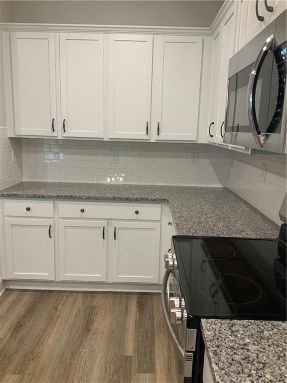 kitchen with white cabinets, backsplash, dark hardwood / wood-style flooring, and stainless steel appliances