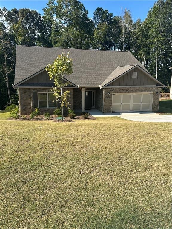 view of front of house with an attached garage, a shingled roof, concrete driveway, board and batten siding, and a front yard