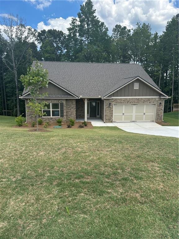 view of front facade with board and batten siding, a front yard, a shingled roof, and a garage