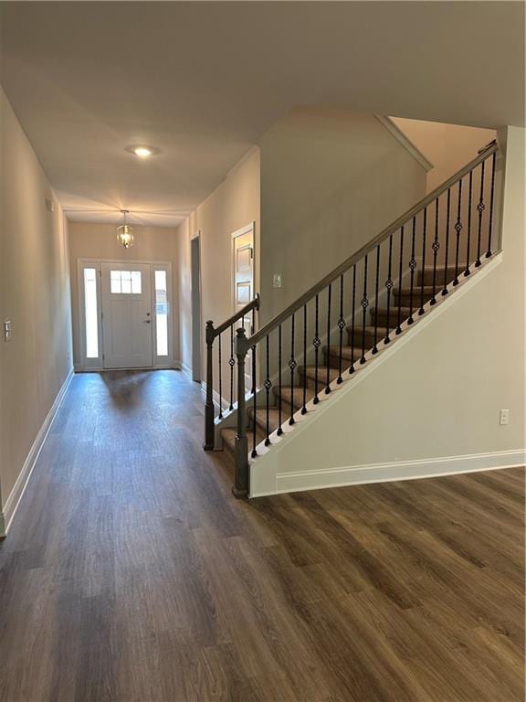 entryway featuring a chandelier, dark wood-style flooring, stairway, and baseboards