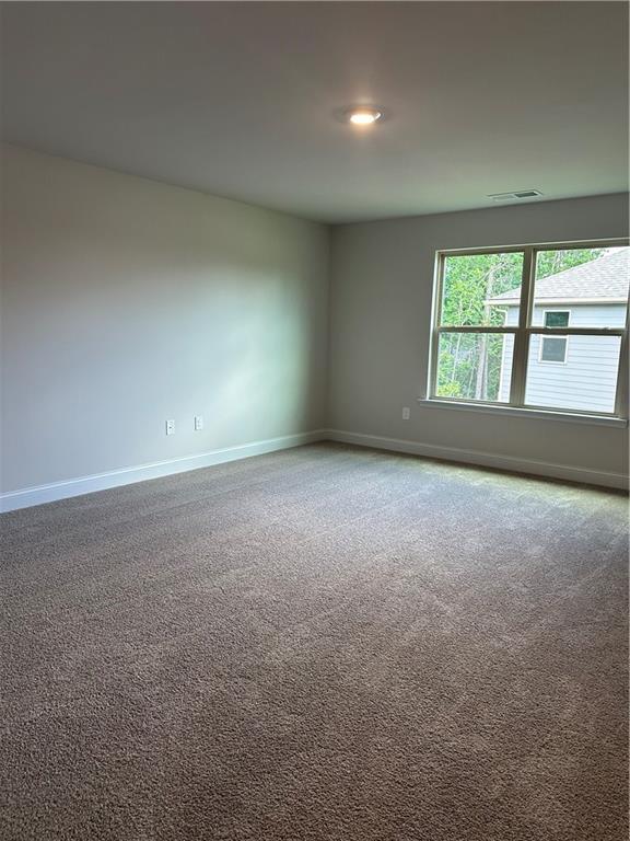 carpeted spare room featuring visible vents and baseboards