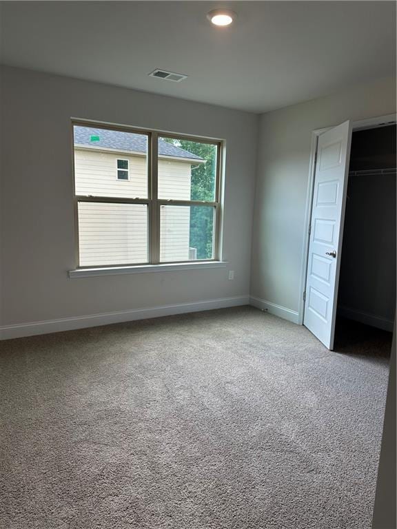 unfurnished bedroom with a closet, carpet, visible vents, and baseboards