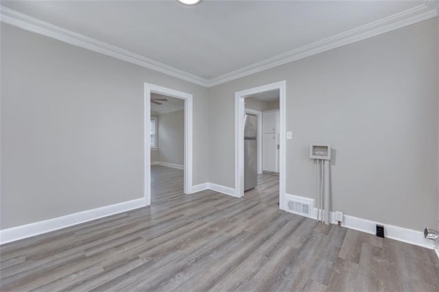 empty room with light hardwood / wood-style floors and ornamental molding