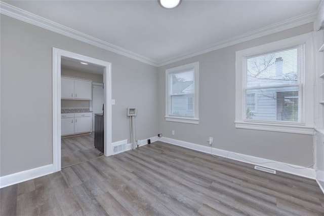 spare room with light wood-type flooring and crown molding