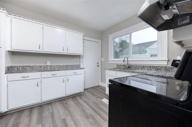 kitchen with sink, white cabinets, light hardwood / wood-style floors, and range hood