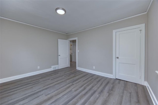 spare room featuring crown molding and light hardwood / wood-style flooring