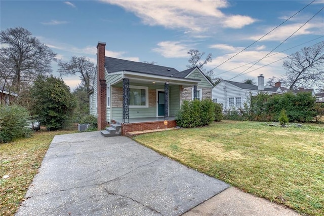 bungalow-style home with a porch, a front yard, and cooling unit