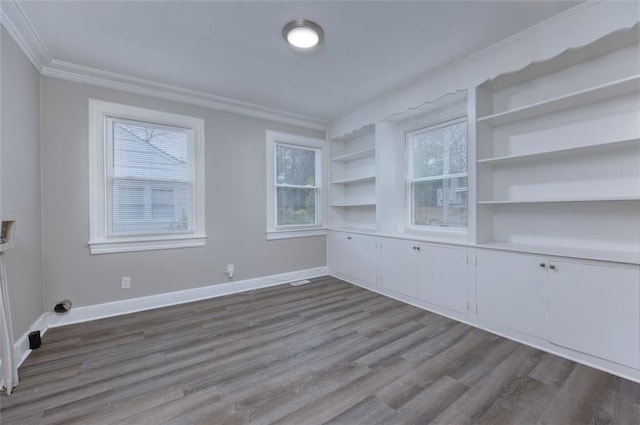 empty room with built in shelves, plenty of natural light, light wood-type flooring, and ornamental molding