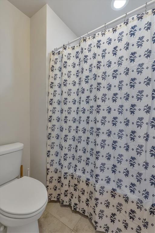 bathroom featuring tile patterned flooring, toilet, and walk in shower