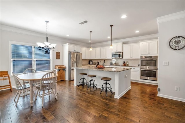 kitchen with a kitchen island, pendant lighting, white cabinetry, a kitchen bar, and stainless steel appliances