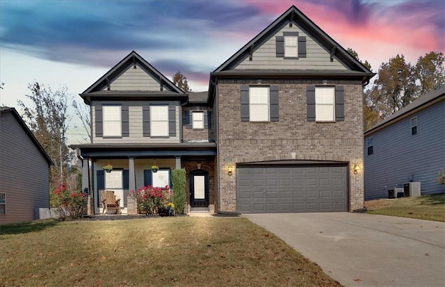 view of front of property featuring a garage, a yard, covered porch, and central air condition unit