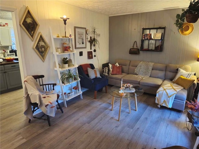 living room featuring wood walls, light hardwood / wood-style floors, and a textured ceiling