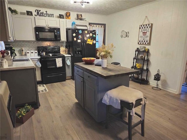 kitchen featuring wood counters, light wood-type flooring, white cabinetry, and black appliances