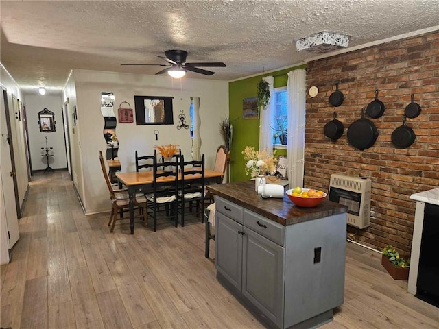 kitchen featuring wood counters, light wood-type flooring, heating unit, ceiling fan, and a center island