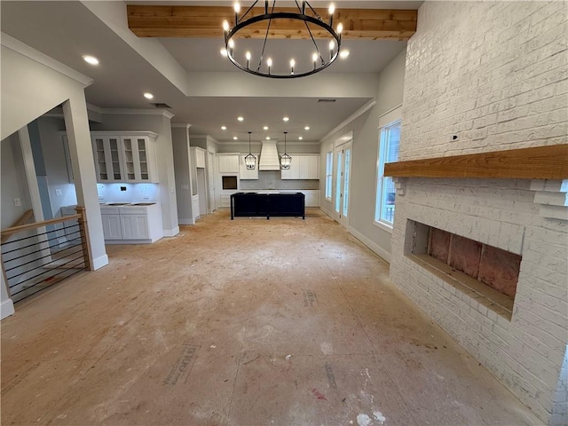 unfurnished living room with baseboards, an inviting chandelier, crown molding, a brick fireplace, and recessed lighting