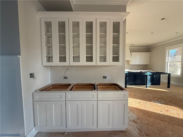 kitchen featuring white cabinetry, ornamental molding, and wall chimney exhaust hood