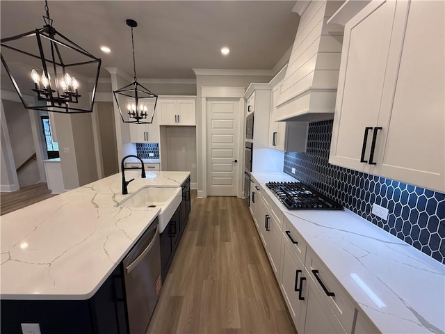 kitchen featuring a sink, stainless steel dishwasher, a chandelier, wood finished floors, and ornamental molding