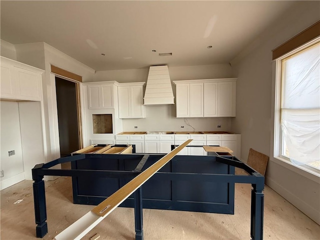 kitchen with a center island, custom range hood, and white cabinets