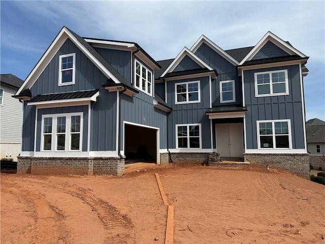 view of front of home with board and batten siding, a standing seam roof, metal roof, a garage, and driveway