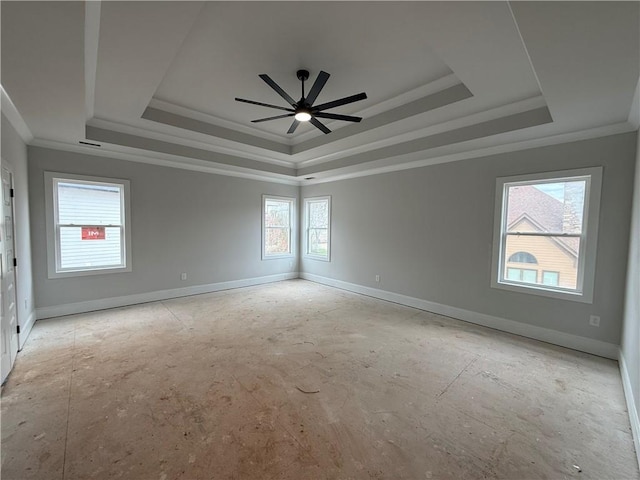 unfurnished room with ornamental molding, a tray ceiling, and baseboards