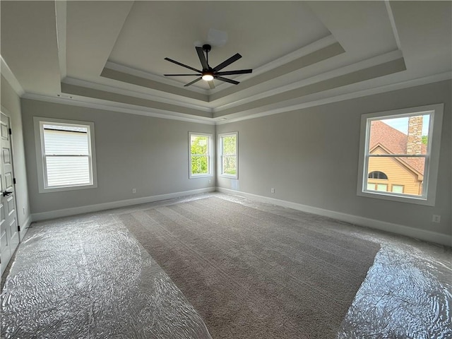 spare room with a tray ceiling, a ceiling fan, crown molding, baseboards, and light carpet