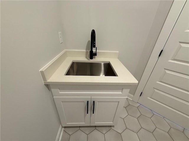 detailed view of a sink, light countertops, and white cabinets