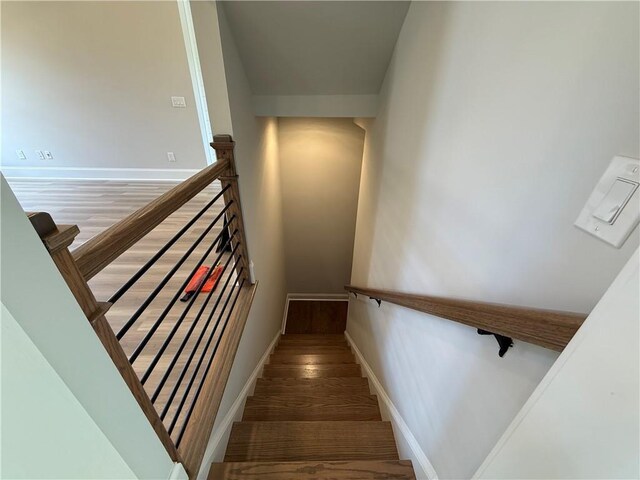 stairway with wood finished floors and baseboards