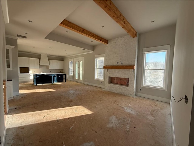 unfurnished living room with beamed ceiling and a stone fireplace