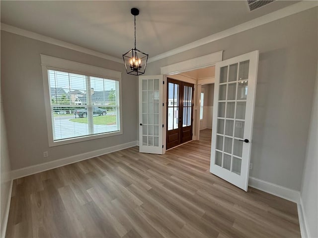 unfurnished dining area with french doors, a chandelier, baseboards, ornamental molding, and wood finished floors