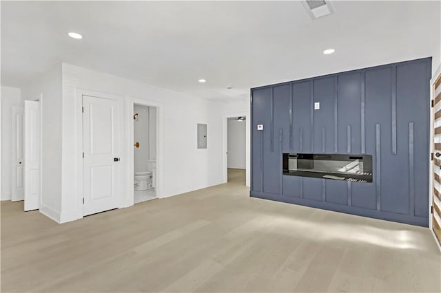 unfurnished living room featuring electric panel and light hardwood / wood-style floors