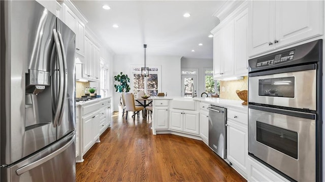 kitchen with appliances with stainless steel finishes, decorative light fixtures, and white cabinets