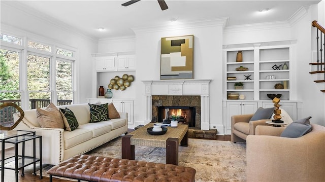 living room featuring crown molding, ceiling fan, a high end fireplace, and light hardwood / wood-style floors